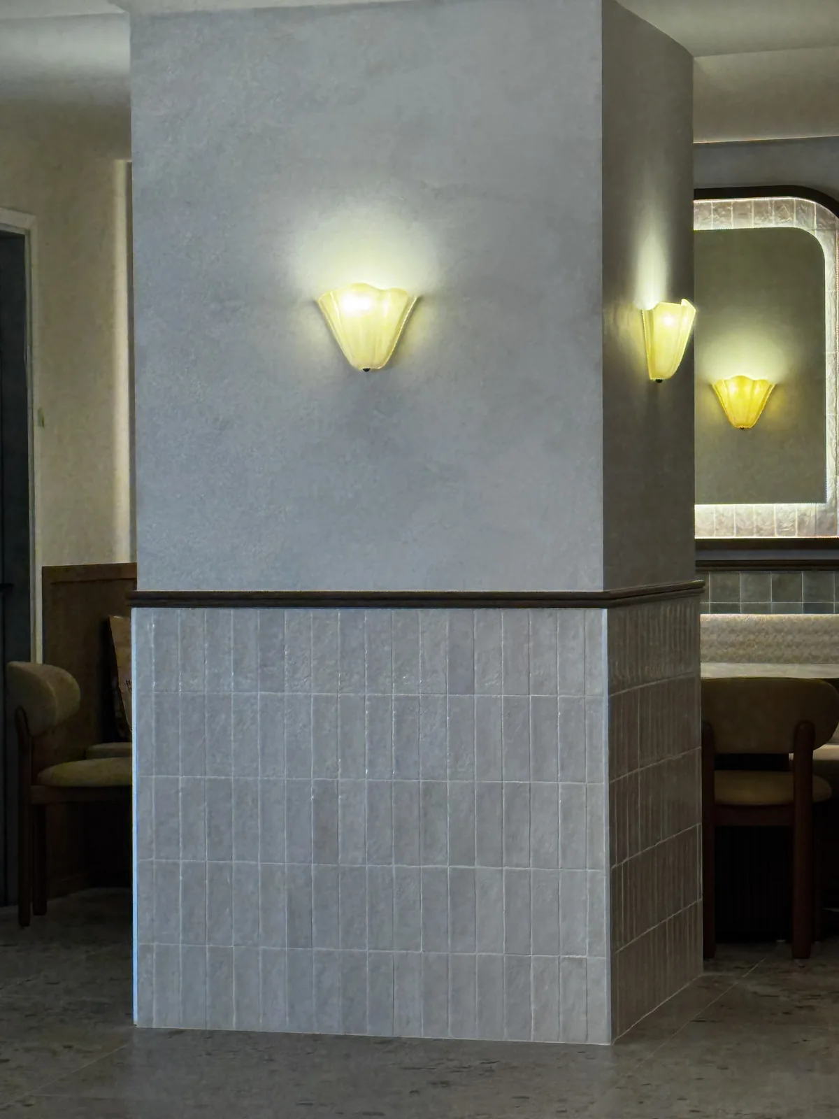 Limewashed column with alabaster sconce above a sage-green ceramic tile base at Cocotte Bistro, Ottawa