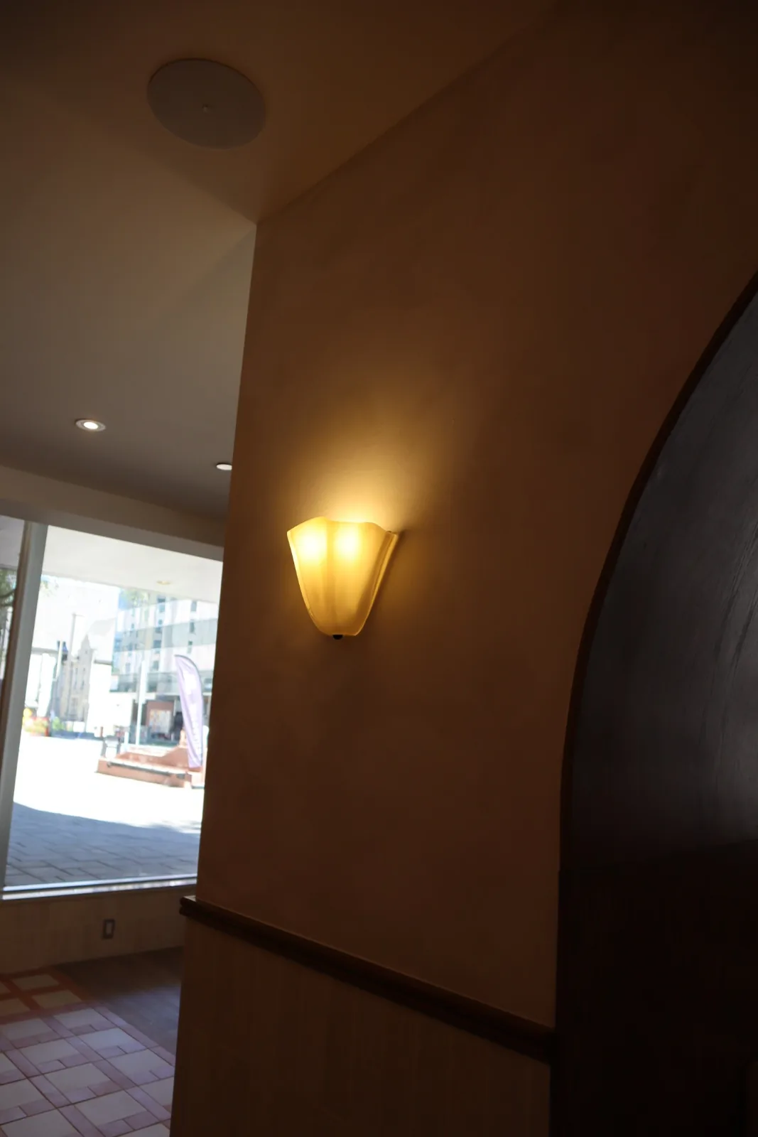 Limewashed entry vestibule with arched opening and warm sconce light at Cocotte Bistro, downtown Ottawa