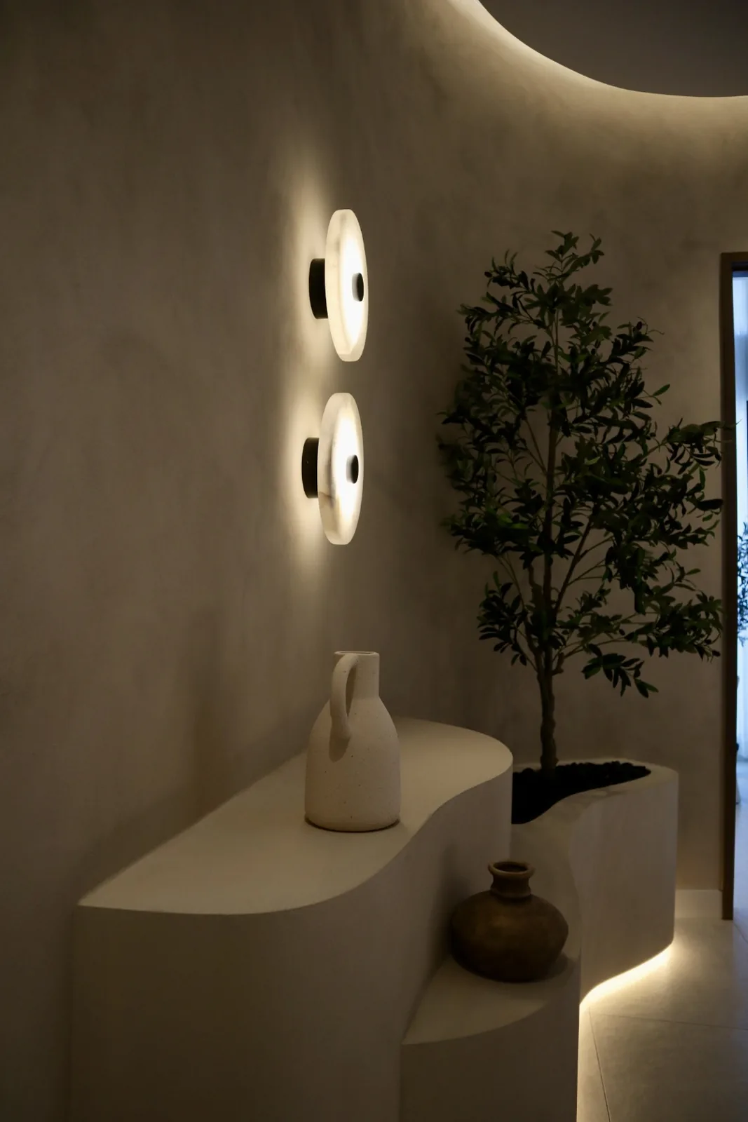 Limewash walls under warm evening lighting with alabaster sconces and an underlit sculpted console, Envy Cosmetic Clinic Ottawa