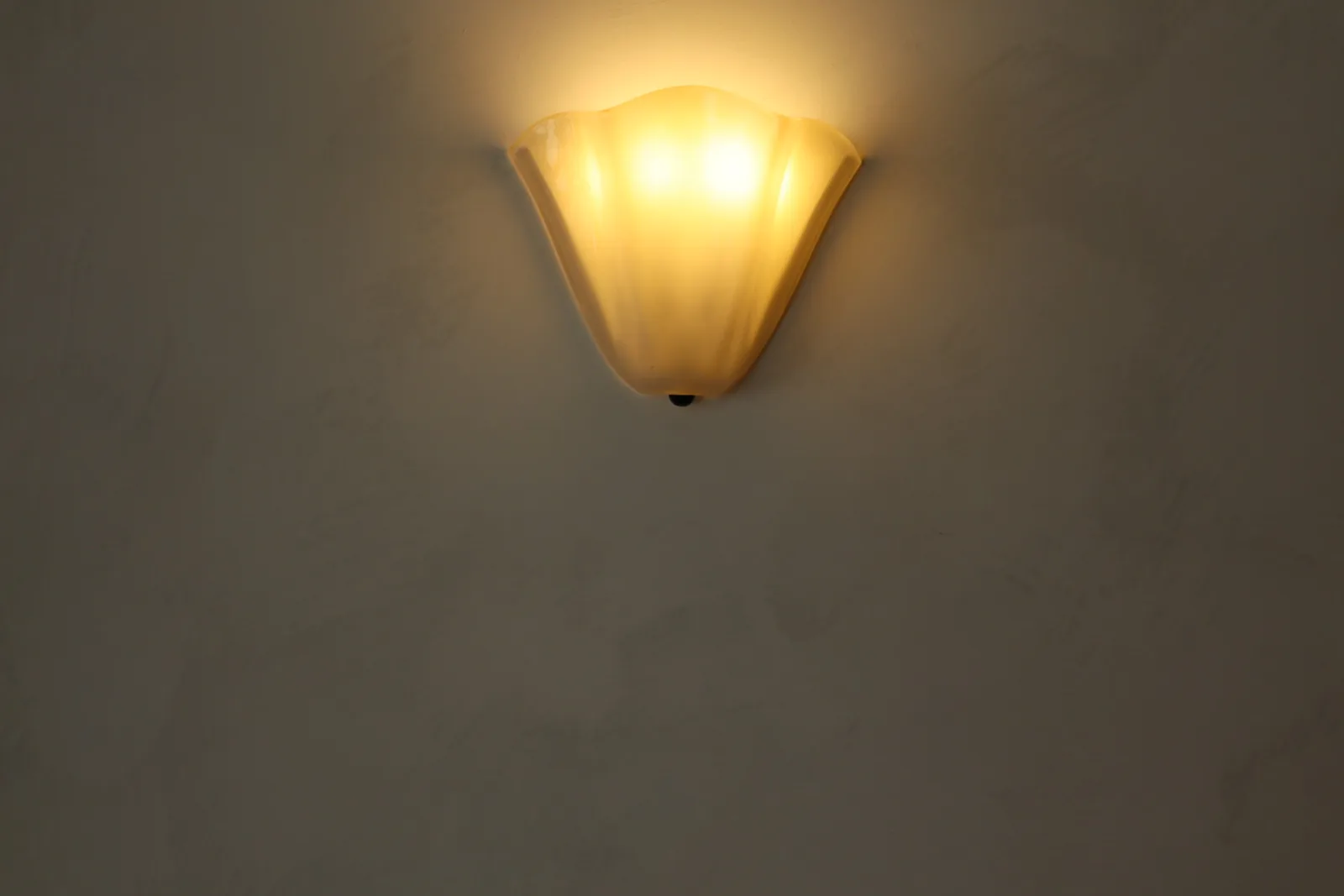 Close-up of soft two-tone limewash texture with a scalloped alabaster sconce at Cocotte Bistro, Ottawa
