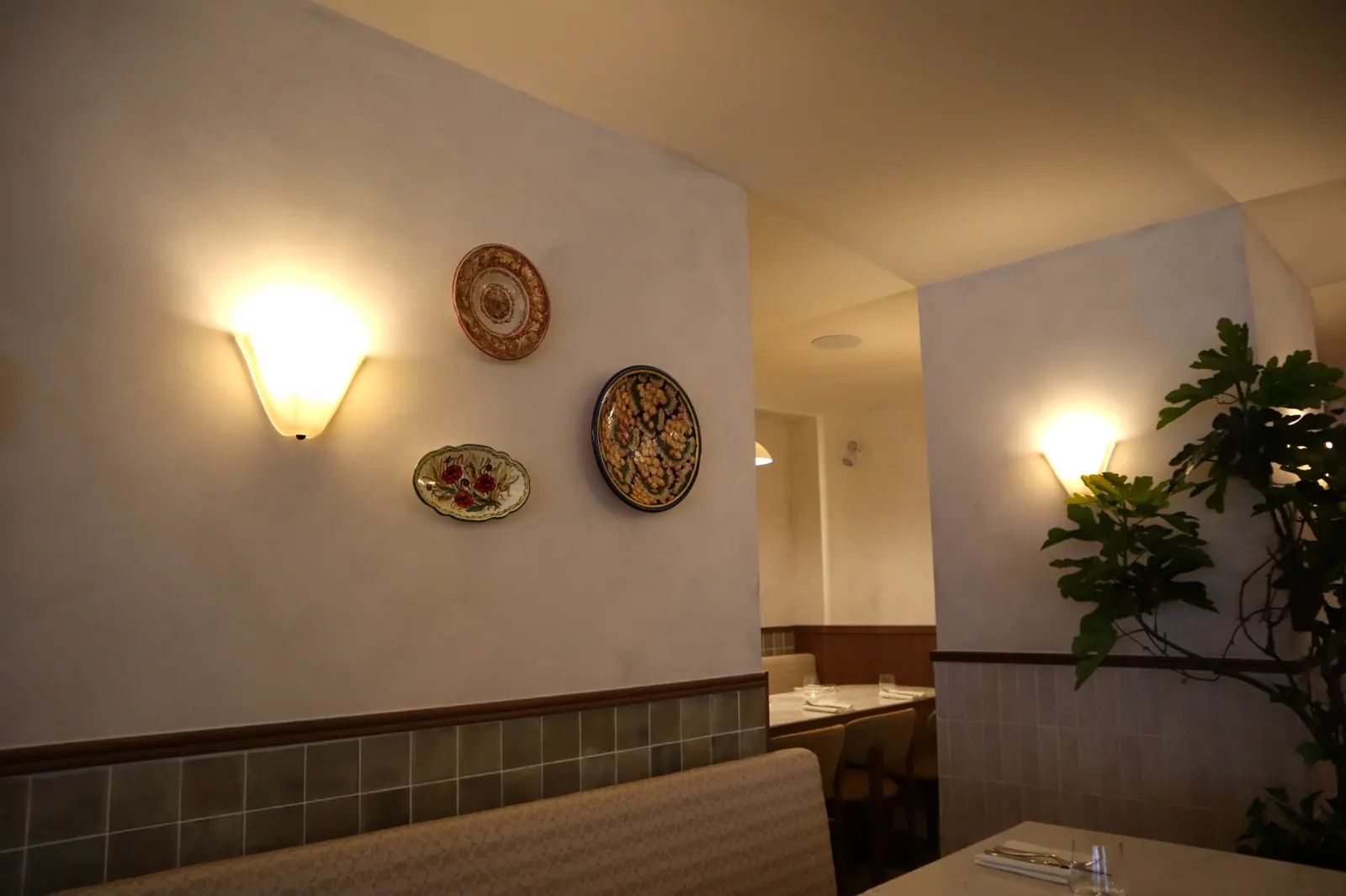 Limewash feature wall with sconces and ceramic plates at an Italian restaurant in Ottawa
