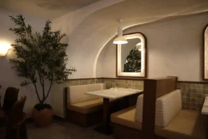 Light two-tone limewash walls and arched cove above banquette seating at Carletto restaurant, Ottawa