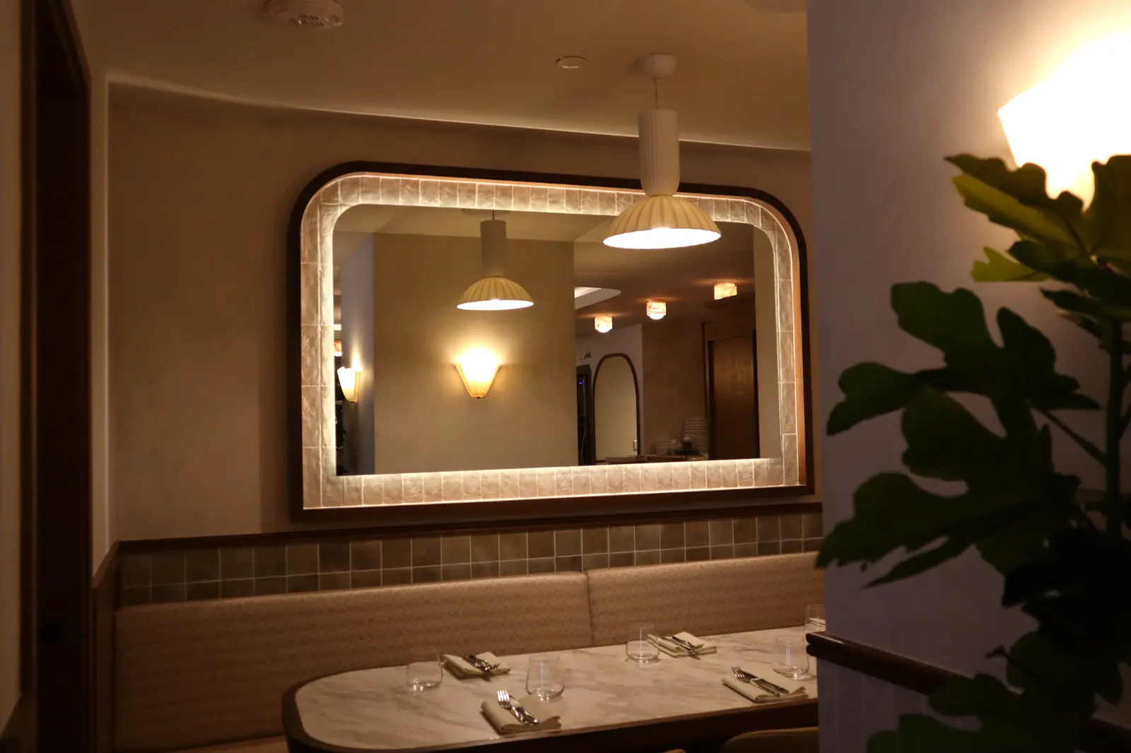 Smooth limewash wall with lit arched mirror and pendant at Carletto Ottawa