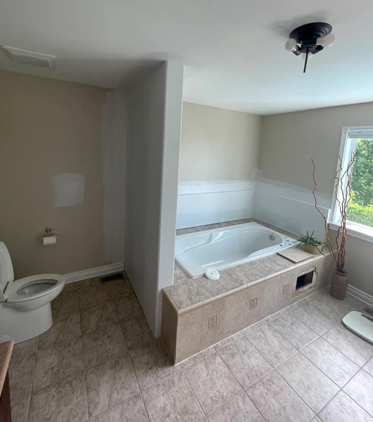 Kanata ensuite before microcement: beige ceramic floor and tiled drop-in tub deck with decorative inserts
