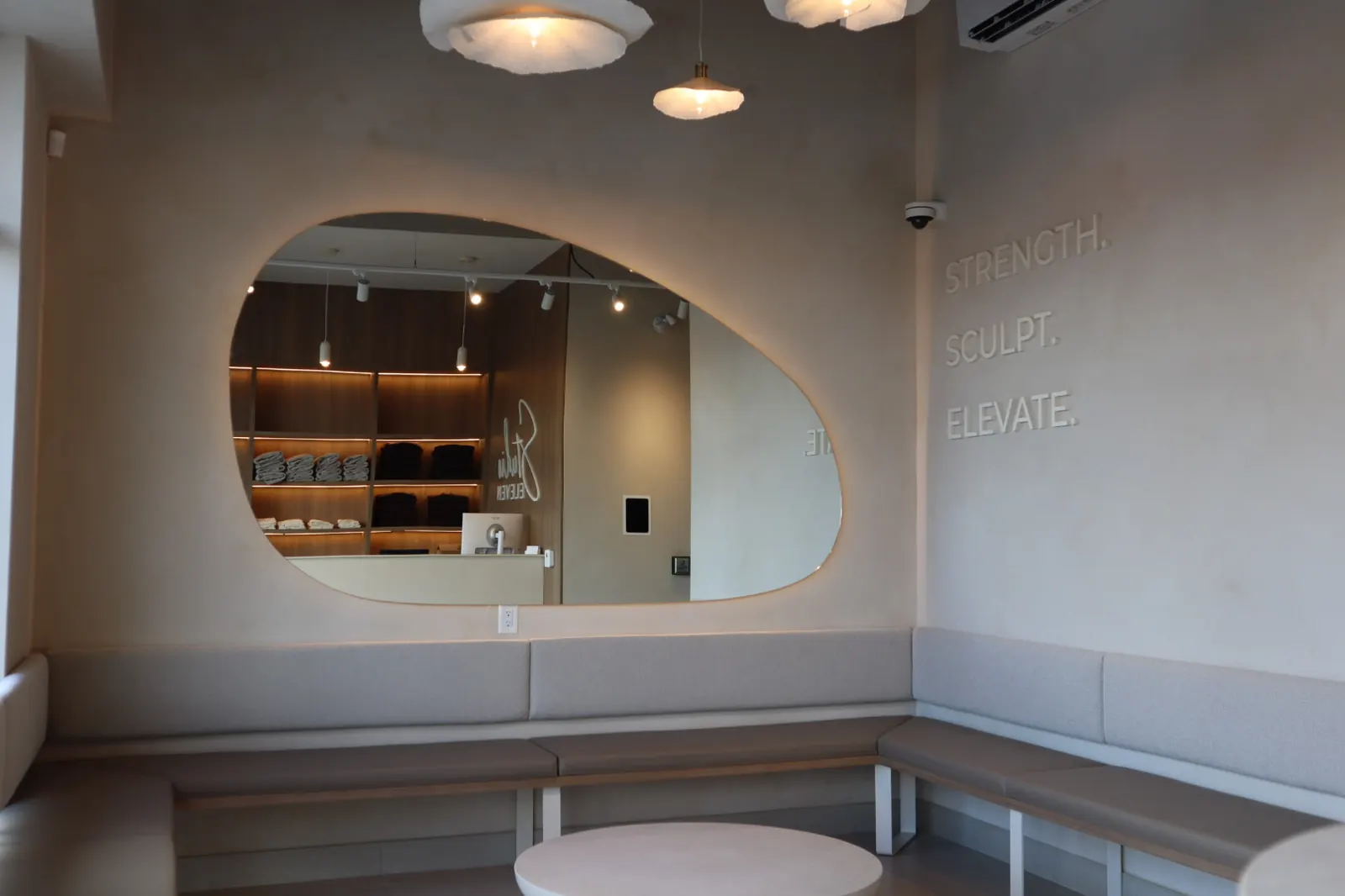 Limewash lounge wall with recessed organic mirror and bench seating at an Ottawa pilates studio