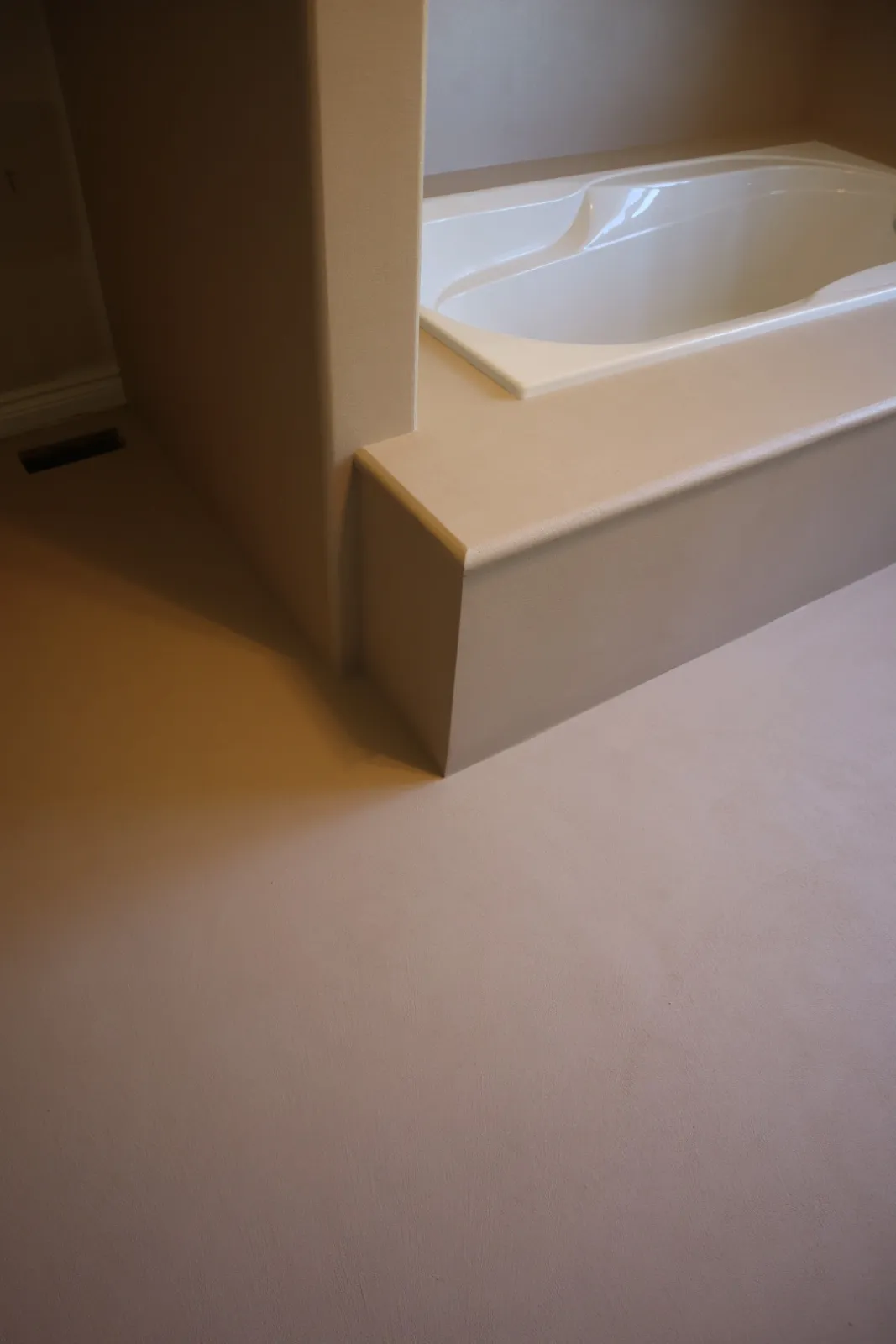 Hand-shaped rounded microcement tub deck edge meeting a half wall in a Stittsville area ensuite