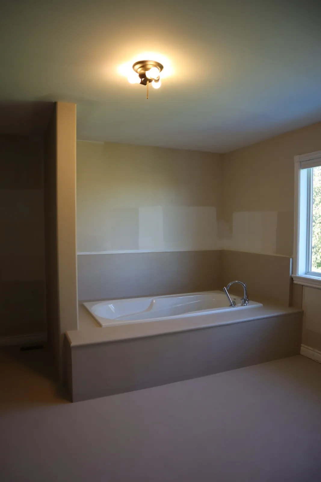 Drop-in tub deck, apron and surround band finished in microcement over tile in a Kanata bathroom