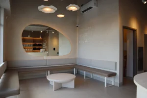 Reception lounge at Studio Eleven Pilates Ottawa with two-tone sandy limewash walls, organic mirror and built-in bench
