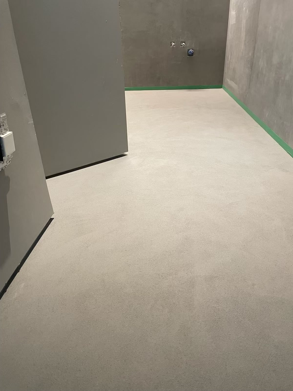 Concrete effect plaster finish applied to interior wall surface showing textured grey-toned coating with industrial aesthetic