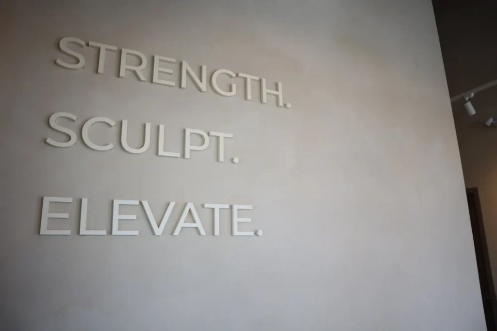 Strength Sculpt Elevate dimensional lettering mounted on a two-tone sandy limewash feature wall in Ottawa