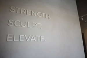Strength Sculpt Elevate dimensional lettering mounted on a two-tone sandy limewash feature wall in Ottawa